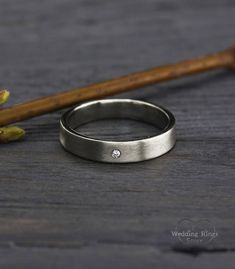 a close up of a ring on a table next to some flowers and a wooden stick