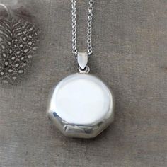 This sleek, modern locket has a unique round octagon shape.  The sterling silver pendant is a bit thicker than most.  Opening reveals two frames in which to place your beloved photographs.  The pendant is set on a new belcher chain which is adorned at the clasp with tiny gems (as shown with aquamarine).  Customize your necklace by selecting your gem/birthstone of choice at checkout.Locket  29mmNecklace length 24" (61cm)Birthstones:January - GarnetFebruary - AmethystMarch - AquamarineApril - Crys Luxury Sterling Silver Round Locket Necklace, Cheap Silver Round Locket Necklace, Silver Round Locket Necklace With Detachable Pendant, Silver Round Minimalist Locket Necklace, Minimalist Silver Round Locket Necklace, Silver Octagon Engraved Jewelry, Silver Medallion Locket Necklace With Detachable Pendant, Minimalist Silver Locket Necklace With Round Pendant, Silver Locket Necklace With Polished Round Pendant