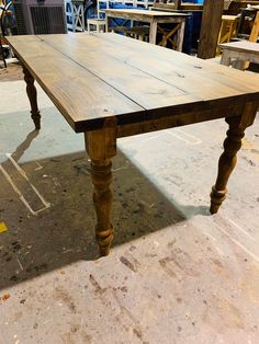 an old wooden table is sitting in the middle of a room with other tables and chairs