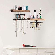 a white dresser with jewelry hanging from it's sides and two wooden shelves on the wall