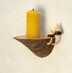 a yellow candle sitting on top of a wooden shelf next to a wall mounted hook