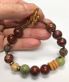 Vintage Chinese Carved Bone Beads,Vintage Brecciated Jasper Stone Beads, Vintage Moss Jasper Stone Beads,Vintage Antiqued Brass Ornate Filigree Beads,  Gorgeous AA grade 12mm or approximately 1/2" in diameter brecciated jasper beads in shades of brown,burgundy red and cream and 12mm moss green jasper beads are the basis for this asymmetrical bracelet which draws upon nature for its inspiration. The beads have a beautiful high polish as you can see in the photos. In brecciated jasper, rich browns, cremes and shades of brick or burgundy red are swirled through the stone in an amazingly wide range of patterns.  Usually considered as chalcedony, jasper is found all over the world. Brecciated jasper is so named because of its resemblance to a rock known as breccia, which consists of angular and Red Bead Bracelet, Brecciated Jasper, Red Beaded Bracelet, Carved Bone, Green Jasper, Bone Beads, Bone Carving, Bracelet Vintage, Jasper Beads