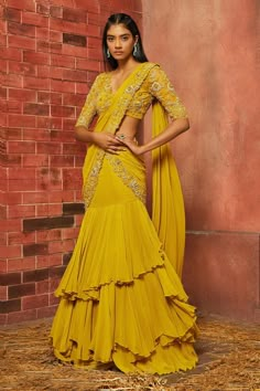 Mustard pre-draped saree with embellished floral motifs on border. Comes with blouse. Component: 2 Embellishment Neckine: V neck Sleeve Length: Elbow Fabric: Georgette, Net Color: Yellow Lining material: Crepe Fishtail hem with ruffle deatil on saree Embellished floral motifs on blouse Back cutout detail with tie-up detail on blouse - Aza Fashions Yellow Ruffle Saree For Haldi, Yellow Ruffle Saree, Yellow Haldi Outfit, Yellow Sari, Haldi Ceremony Outfit, Haldi Dress, Haldi Outfits, Pengantin India, Net Blouse