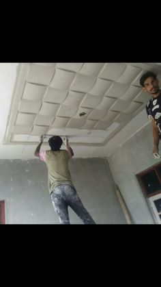 two men are painting the ceiling in an empty room