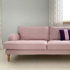 a pink couch sitting in front of a window