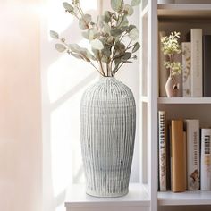 a vase with some flowers in it sitting on a shelf next to a bookshelf