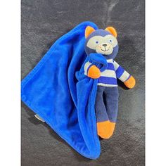 a teddy bear wrapped in a blue towel on top of a black surface with a white and orange stripe