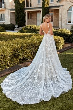 a woman standing in front of a house wearing a wedding dress with an open back