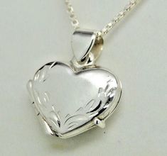 "Photos are precious and here's a lovely way to keep those memories close. Our beautifully worked genuine 925 sterling silver heart picture locket has a hand engraved leaf border along the heart shape itself - so each is a unique work of art. There's also a secure compartment inside to hold two special photos. Our picture locket in genuine sterling silver is small, measuring approx. 5/8\" wide by 3/4\" long - it works as a pendant or as a charm on a bracelet. A lovely piece of jewelry for a youn Luxury Sterling Silver Locket Necklace, Silver Heart Pendant Locket Necklace With Hallmark, Silver Jewelry With Engraving Option For Valentine's Day, Classic Heart-shaped Sterling Silver Locket Necklace, Classic Heart Shaped Sterling Silver Locket Necklace, Classic Sterling Silver Heart Locket Necklace, Silver Heart Locket Necklace For Anniversary, Silver Round Heart Necklace Keepsake, Silver Double Heart Locket Necklace