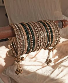 a stack of bracelets sitting on top of a wooden pole next to a white sheet