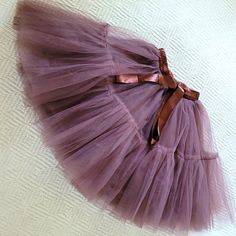 a purple tulle skirt with a brown bow on the waist and bottom, laying on a white surface