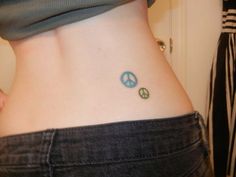 a woman with a small tattoo on her lower back that has two peace signs painted on it