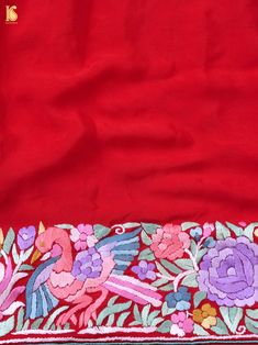 an embroidered red cloth with flowers and birds on the border is shown in this image