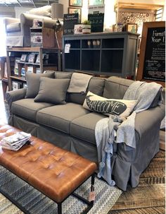 a couch and ottoman in a room with bookshelves, rugs and other items