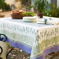 a table that has some plates on it with plants in the back ground behind it