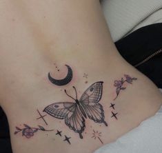 a woman's stomach with a butterfly and moon tattoo on the back of her belly