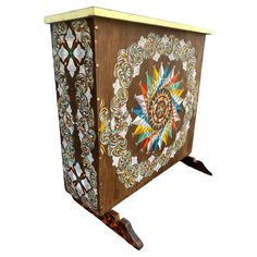 an artisticly designed wooden box with decorative designs on the front and sides, against a white background