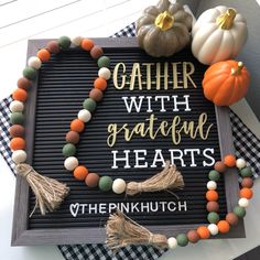 a sign that says gather with grateful hearts and pumpkins on the front door mat