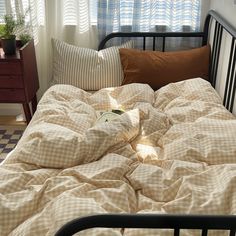 an unmade bed in a bedroom with checkered bedspread and pillows on it