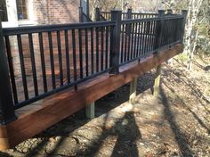 a wooden deck with metal railings in front of a brick building