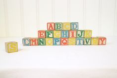 colorful wooden blocks spelling the alphabet on a white surface