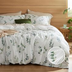 a bed with white and green comforters in a room next to a wooden headboard