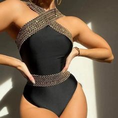 a woman in a black one piece swimsuit with gold chains on the bottom and sides