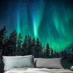 a bed with pillows and blankets in front of an aurora bore wall mural on the wall