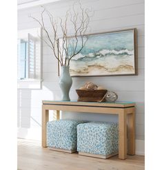 a blue vase sitting on top of a wooden table next to a painting and two stools