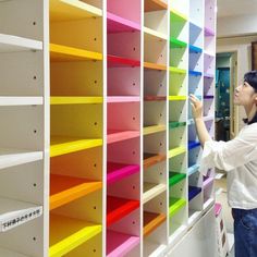 a woman standing in front of a colorful book shelf