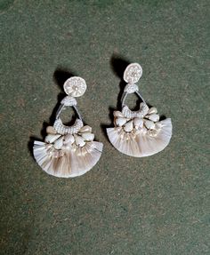 two pairs of earrings with white beads and tassels