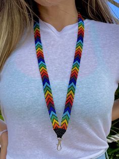 a woman wearing a white shirt is holding a multicolored lanyard with a silver clasp