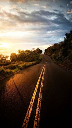 the sun is setting on an empty road with no cars or people driving down it