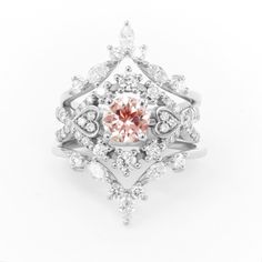 a pink diamond ring with white diamonds on the sides and an intricate design around it