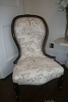 an old chair is sitting on the floor next to a vase with flowers in it