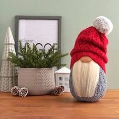 a gnome with a red hat sitting next to a potted plant on a table