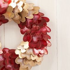 a close up of a wreath on a white wall with red and gold flowers in it