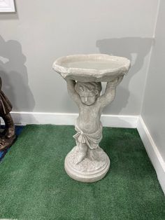 a white pedestal with a bird bath on it's side in the corner of a room