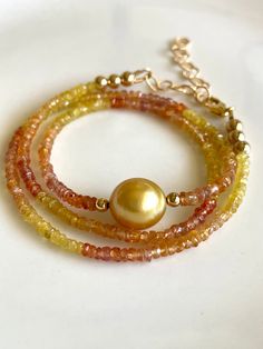 Petite sapphires, 2-4mm, ranging in color from yellow to peach, orange, and red, frame a gorgeous 10mm gold South Sea pearl.   The golden color is intense! Necklace measures 16" with 14K gold-filled findings, and comes with a 2" gold-filled extender chain to bring it to 18".  Works great as a versatile layering piece, or shines all on its own.   Your jewelry will come gift-boxed, and gift-wrapping is available upon request.  Thanks for checking out my shop! Gold Briolette Gemstone Pearl Necklace, Gold Briolette Pearl Necklace With Gemstone, Gold Faceted Pearl Necklace Gift, Yellow Gemstone Round Beads Jewelry, Yellow Gemstone Jewelry With Round Beads, Yellow Gold Pearl Necklace With Gemstone, Gold Single Strand Gemstones As Gift, Elegant Gold Round Bead Gemstones, Elegant Gold Gemstones With Gemstone Beads