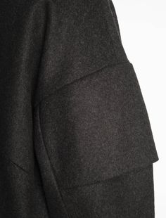 Dubhé is an oversize coat. The armhole is drooping, and the sleeves are slightly rounded. Each coat has a yoke on each shoulder reminiscent of Japanese armor, which gives volume to the silhouette. The sleeves are cut to fit the pleats with our logo. The collar is made up of two flaps that cross each other and close with buttons. The overall volume is rounded, although narrower towards the bottom of the coat. There are two large diagonal pockets, consistent with the rest of the collection. Finall Luxury Oversized Wool Outerwear, Luxury Oversized Outerwear With Double Button Closure, Luxury Oversized Pea Coat With Pockets, Luxury Oversized Dark Wash Outerwear, Yuppie Fashion, Dark Grey Coat, Japanese Armor, Oversize Coat, Drape Pants