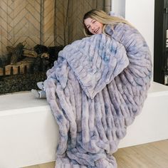 a woman in a fur coat standing by a fireplace with her hands on her hips