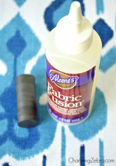 a bottle of fabric glue sitting on top of a blue and white rug