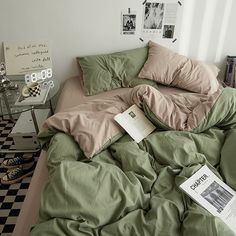 an unmade bed with sheets and pillows on it, next to a paper book