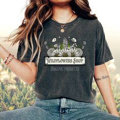 This vintage-inspired t-shirt features a beautiful wildflower garden graphic, perfect for nature lovers and those who appreciate a touch of nostalgia. Made from soft and comfortable material, this t-shirt is perfect for casual outings or lounging at home. The unique design and classic fit make it a wardrobe staple for any vintage or nature-inspired fashion enthusiast. This Comfort Colors Tee is made of soft-washed, garment-dyed fabric bringing extra coziness to your wardrobe while the relaxed fi Organic Short Sleeve T-shirt For Spring, Vintage Short Sleeve T-shirt With Plant Print, Vintage Relaxed Fit T-shirt With Plants Print, Vintage Cotton T-shirt With Plant Print, Vintage T-shirt With Plant Print, Short Sleeve, Organic Cotton T-shirt For Spring, Relaxed Fit T-shirt For Gardening In Spring, Short Sleeve T-shirt With Plants Print For Gardening, Cotton Graphic Print T-shirt For Gardening