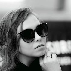 a woman wearing sunglasses is posing for the camera with her hand on her chin and looking off to the side