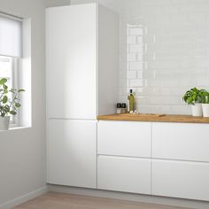 a kitchen with white cabinets and potted plants