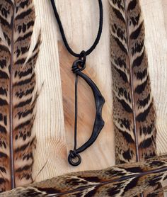 an arrow and some feathers on a wooden table with a black cord hanging from it