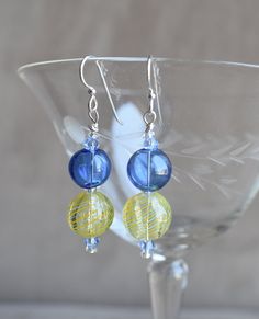 "These Hand Blown Glass Spheres with blue bicone crystals earrings are an excellent Mothers Day, Birthday or Holiday Earring, but are a wonderful everyday earring as well.  The earring has a 2\" drop, and has Sterling Silver ear wires.  The Hand Blown blue color glass bead is approximately 1/2\" (12mm)  in diameter, the hand blown yellow and white swirls bead is approximately 1/2\" (12mm) in diameter.  The crystal Swarovski bicones are 4 mm.  This earring is not heavy or bulky on the ear. The earring comes with sterling silver earwires. However, If you need Niobium ear wires for allergy purposes, please send a message to me with your order/payment. Niobium wire offers outstanding qualities, including being non-reactive with those who have sensitive skin or metal allergies.  The niobium ear Chip Bead Jewelry, Crystals Earrings, Holiday Earring, Chip Beads, Bead Jewelry, Everyday Earrings, Glass Earrings, Glass Bead, Hand Blown Glass