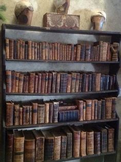 an old bookshelf filled with lots of books and vases on top of it