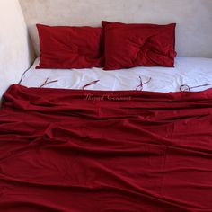 a bed covered in red sheets and pillows